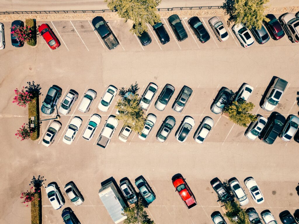 Overhead view of a busy parking lot illustrating the environment where vehicle collisions and parking lot accidents commonly occur