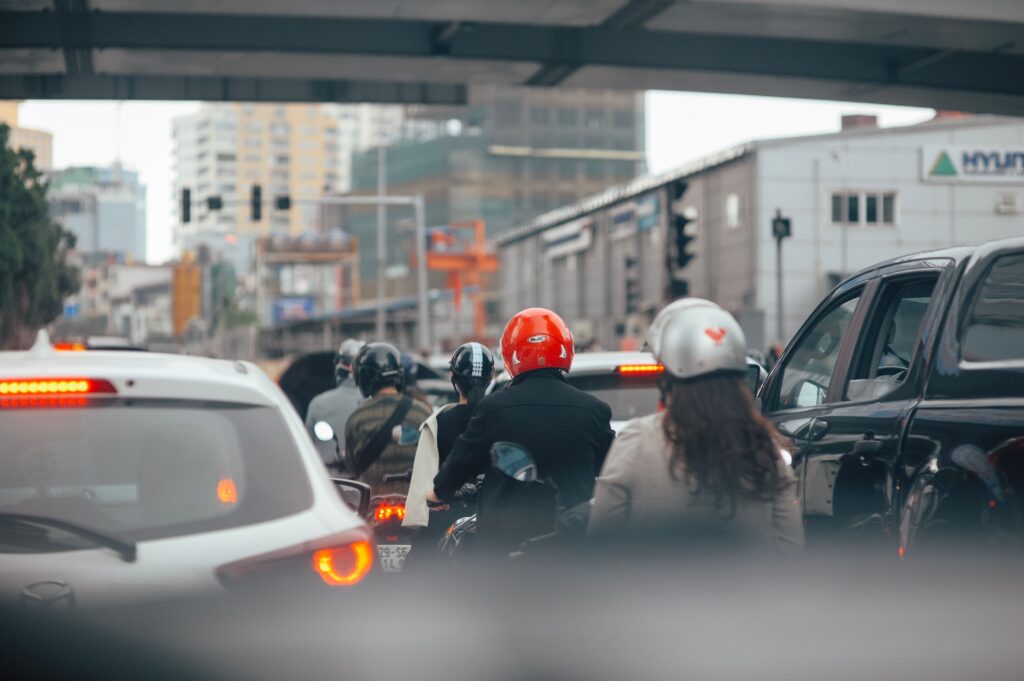 Motorcyclists navigating heavy urban traffic alongside cars and other vehicles