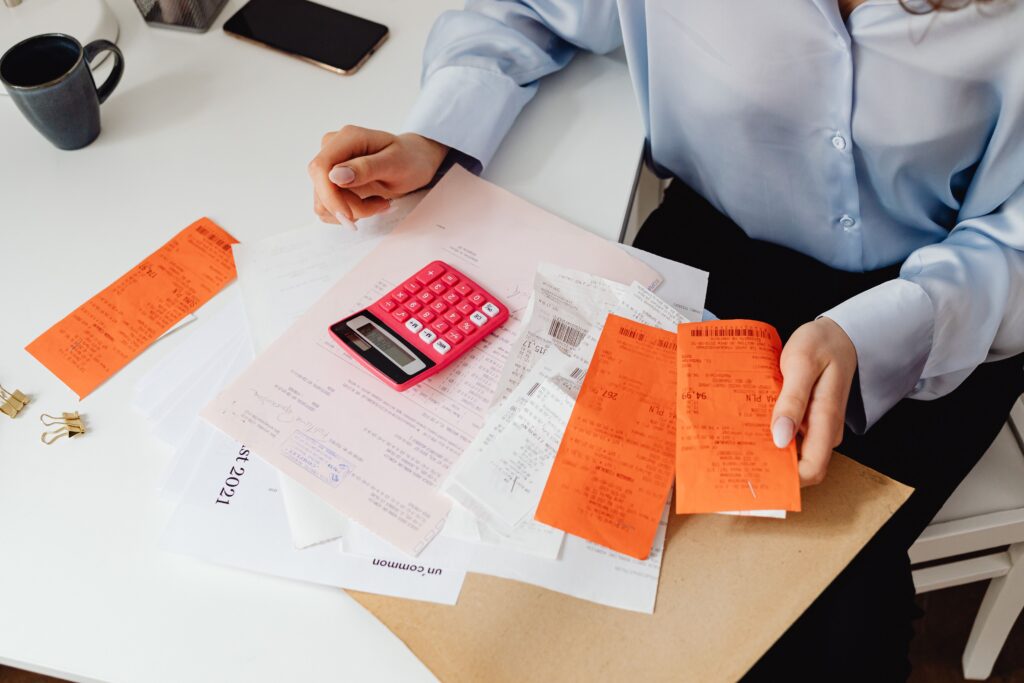 A person using a calculator while reviewing receipts, illustrating the process of calculating expenses and long-term financial costs