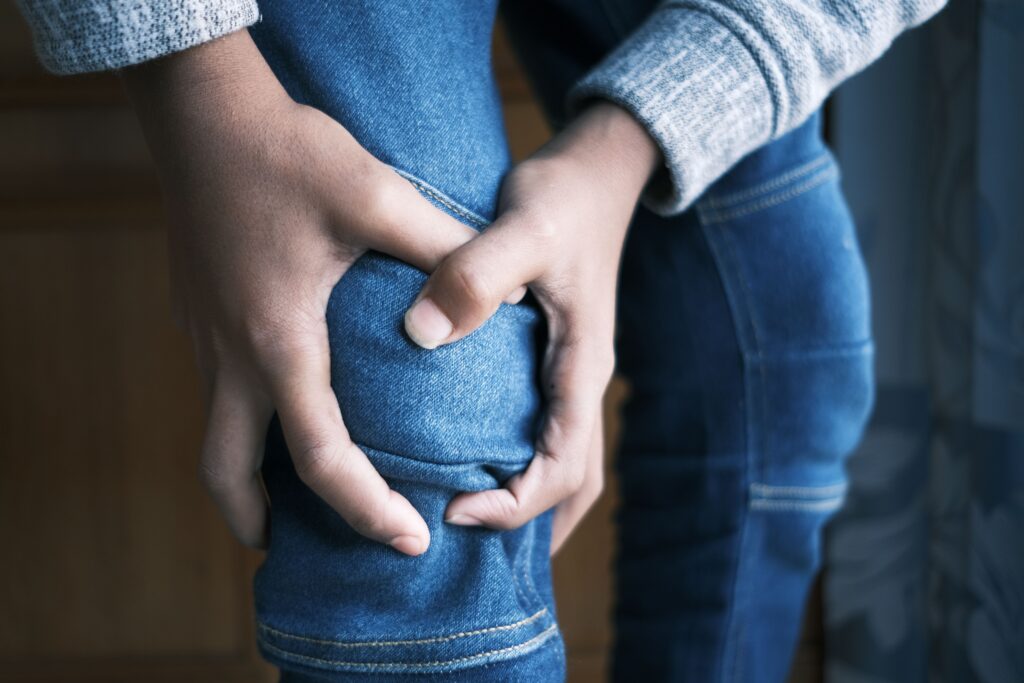 A person holding their knee in pain, illustrating discomfort and the potential impact of a serious injury on mobility