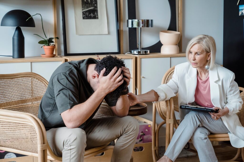 A medical practitioner listens and comforts a troubled man